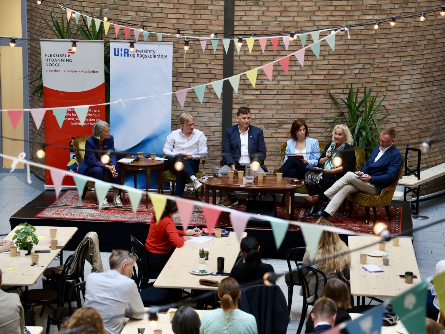 En festlig pyntet scene med et panel og tilskuere i salen