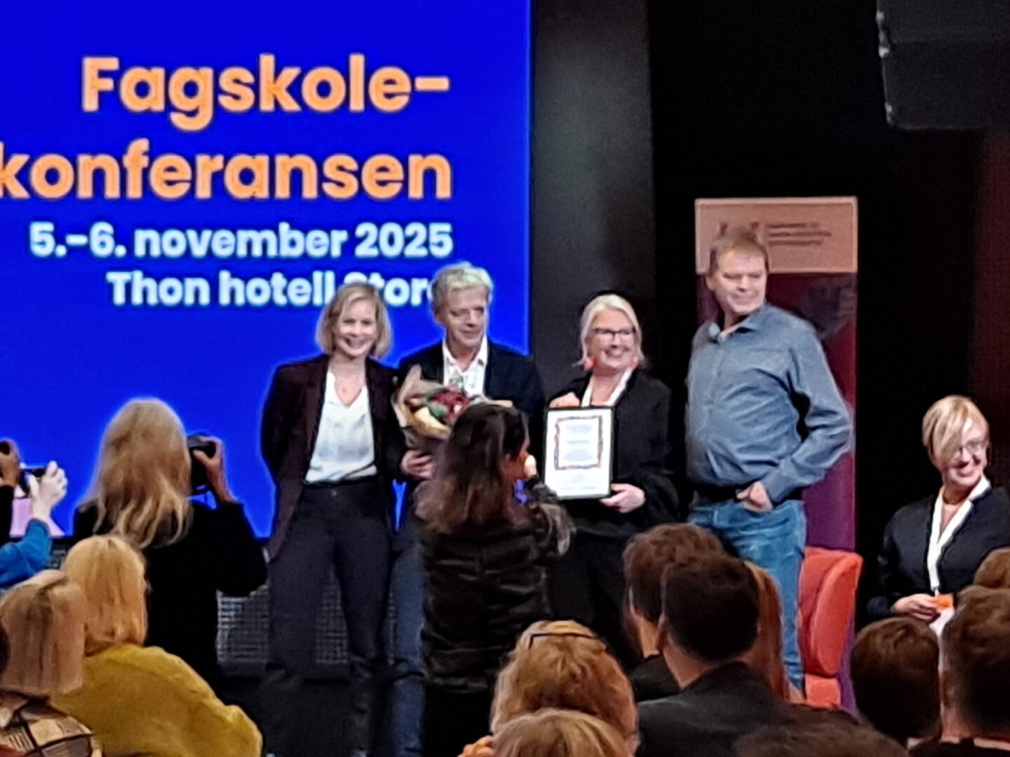 Fire mennesker står på en scene og blir fotografert