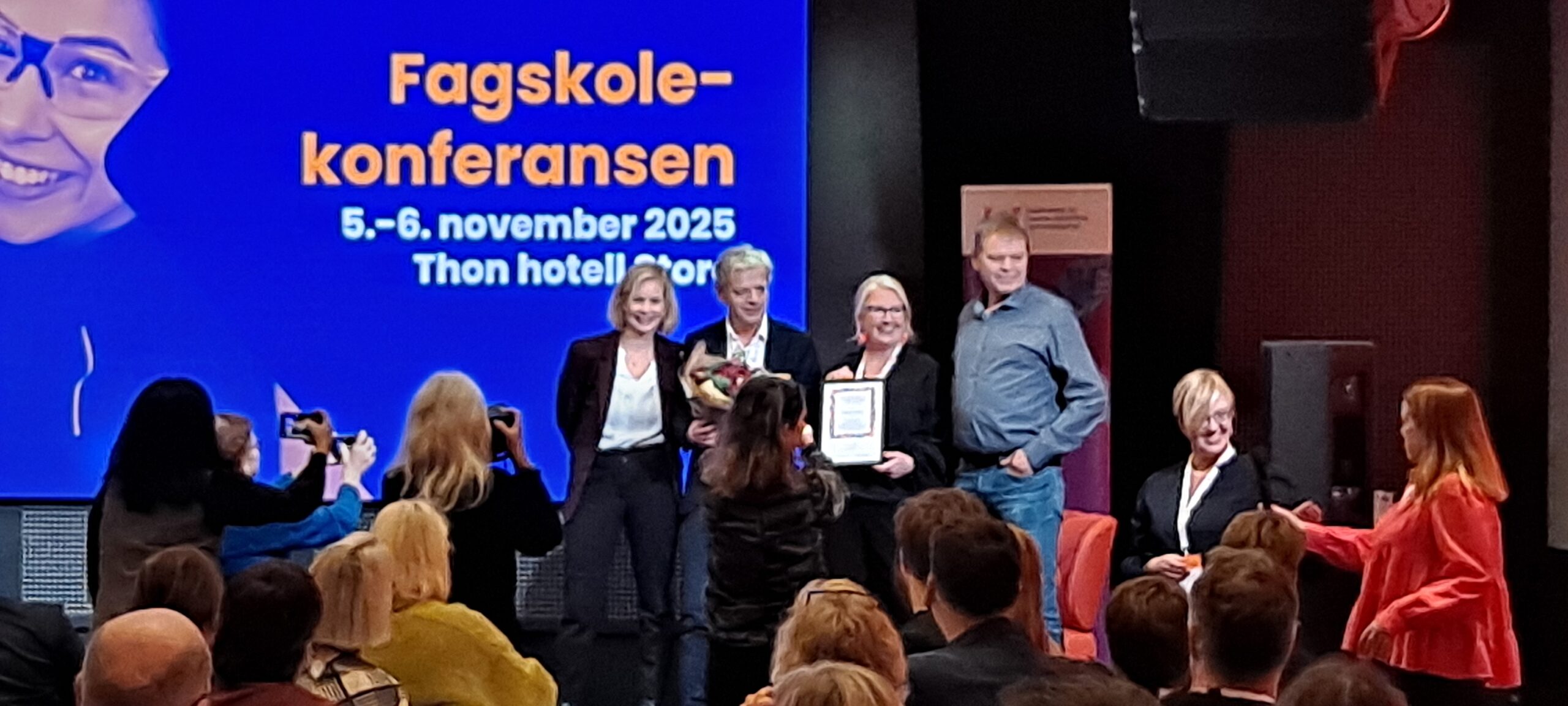 Fire mennesker står på en scene og blir fotografert