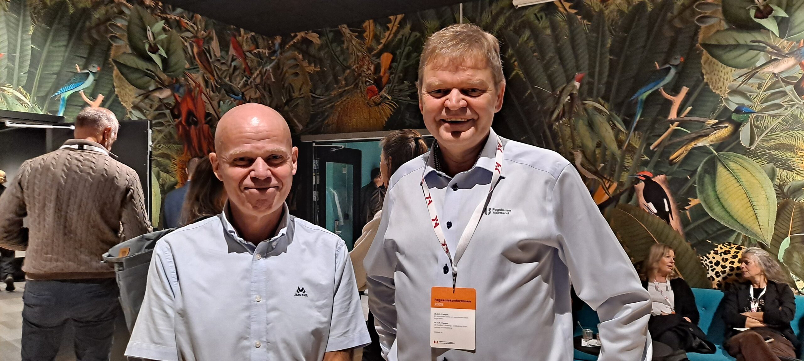 To smilende herrer på konferanse